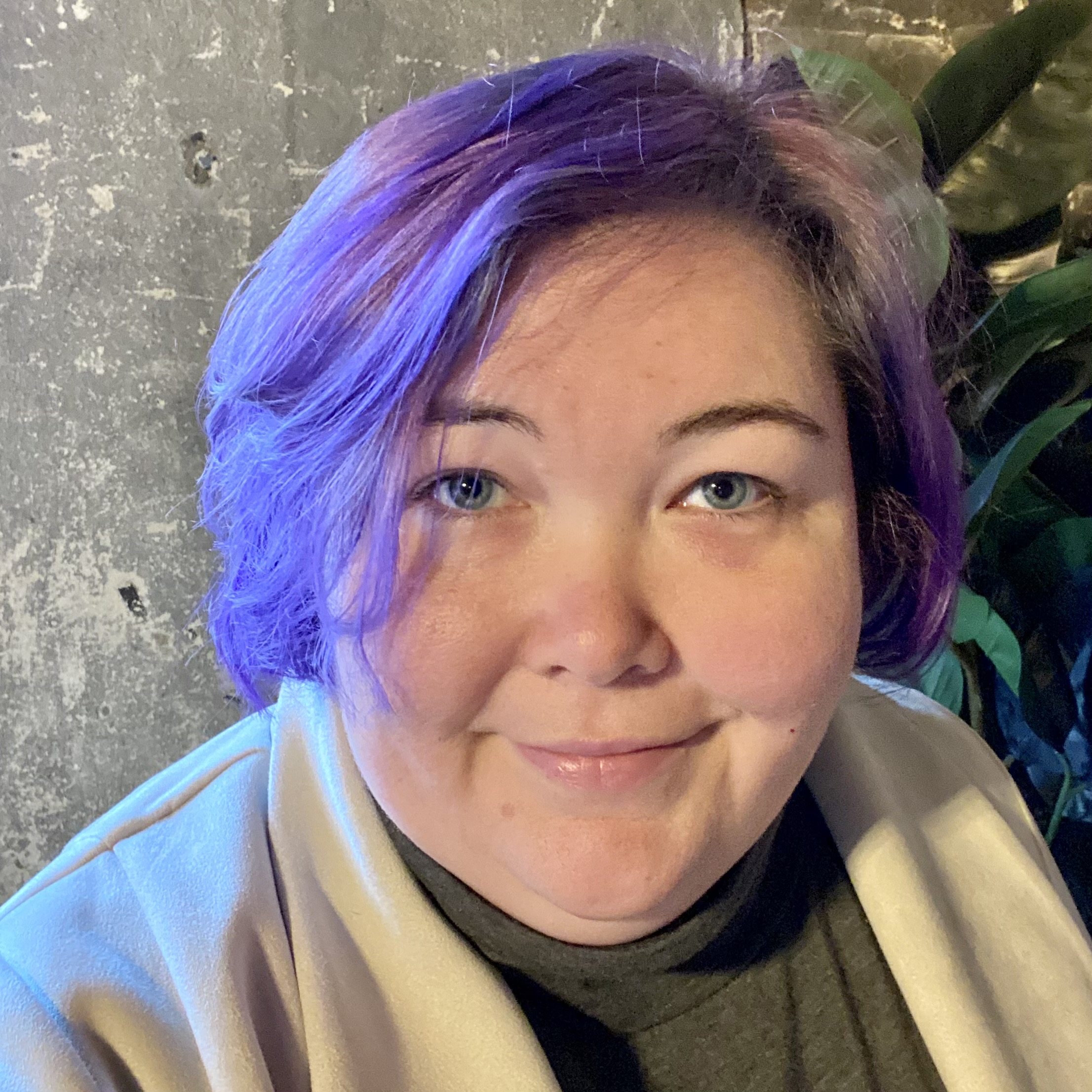 A close up of a white woman (Melissa Batalin) with purple hair looking directly into the camera