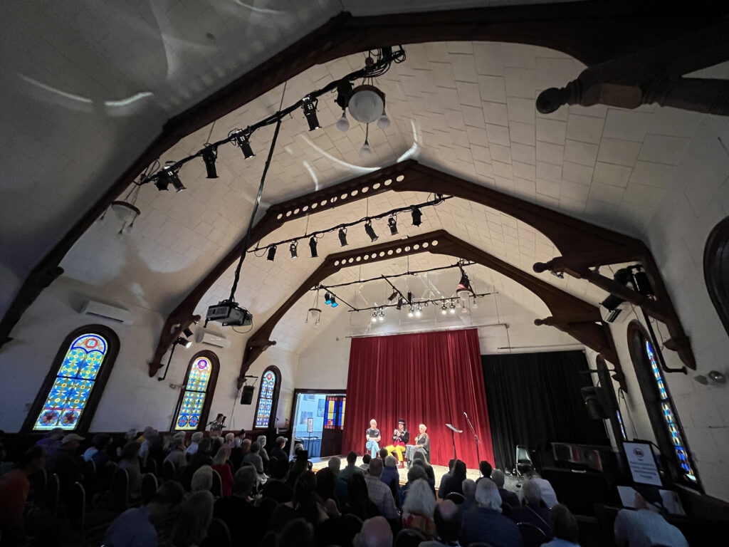 a wide shot of the Sanctuary with a panel on the stage