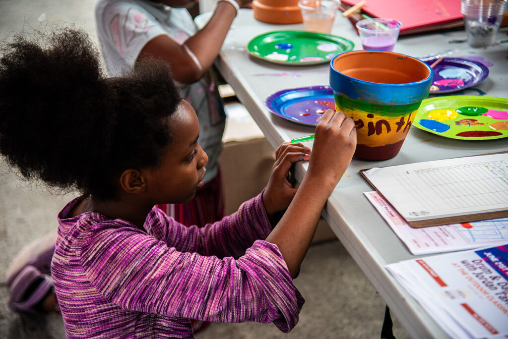 a young girl painting a flower pot
